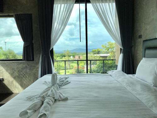 a bedroom with a bed with a large window at Phuwadee Resort Khao Yai in Nong Sarai