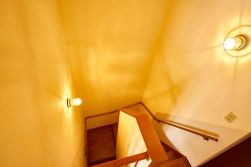 a staircase in a room with a yellow wall at Guesthouse Nijo Fukuro-Tei in Kyoto