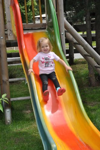 a little girl sliding down a slide on a playground at Restaurant Gästehaus Wiesenheim in Uderns