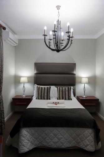 a bedroom with a large bed with a chandelier at Bayswater Lodge in Bloemfontein
