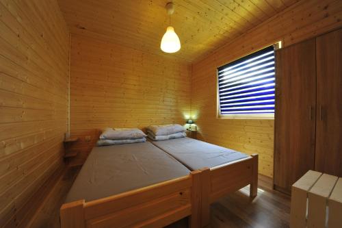 a bed in a wooden cabin with a window at Domki nad Soliną 665-189-444 in Solina