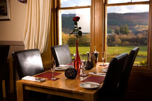 a table with chairs and a vase with a flower on it at Inch Hotel in Fort Augustus