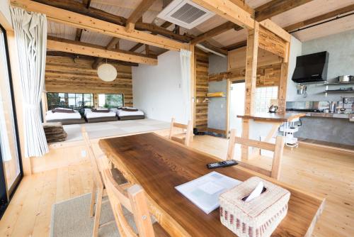 a large room with a wooden table and a living room at Onsen Guesthouse HAKONE TENT in Hakone
