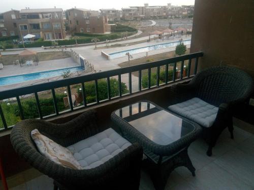 a balcony with two chairs and a table and a pool at Chalet Marina Wadi Degla Families Only Pool view 2nd floor with Roof 6 adults in Ain Sokhna