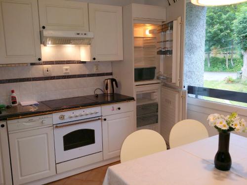 a kitchen with white cabinets and a table with chairs at Konvalinka - ubytování v soukromí in Harrachov