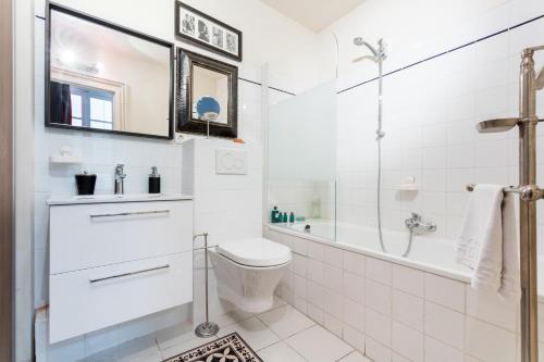 La salle de bains blanche est pourvue d'une baignoire et de toilettes. dans l'établissement Le colonial, à Montpellier