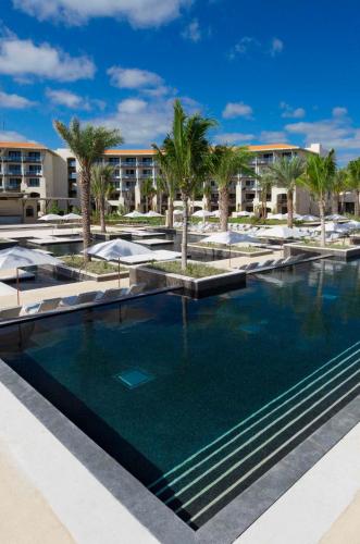 a large swimming pool with palm trees and umbrellas at Unico Hotel Riviera Maya Adults Only in Akumal