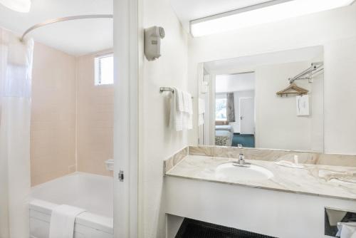 a bathroom with a sink and a tub and a mirror at Days Inn by Wyndham Deming in Deming