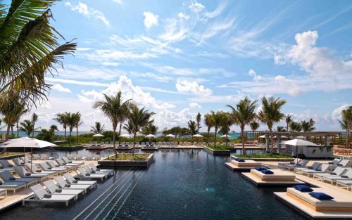a resort swimming pool with lounge chairs and palm trees at Unico Hotel Riviera Maya Adults Only in Akumal