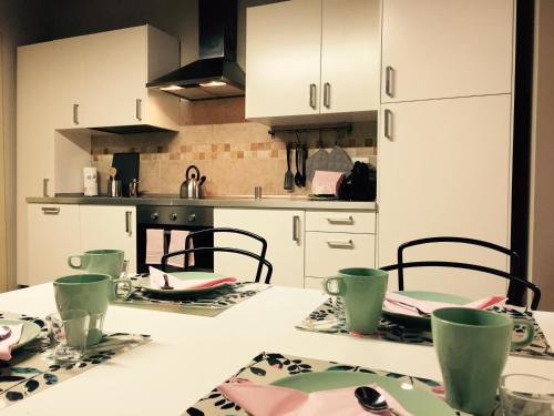a kitchen with white cabinets and a table with plates at Niki O. Apartments in Parma