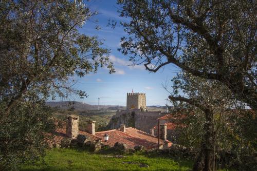 a castle in the distance with trees in the foreground at Casas da Lagariça in Sortelha
