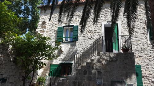 a stone building with green windows and stairs at Villa Cindro House in Podstrana