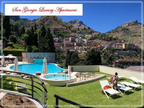 un complexe avec une piscine et une vue sur la ville dans l'établissement San Giorgio Luxury Apartment Taormina-Panoramic Pool & Parking Space, à Taormine