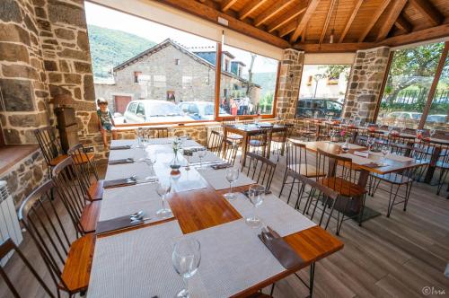 a restaurant with wooden tables and chairs and windows at Hotel Rural La Bolera in Robles de Laciana