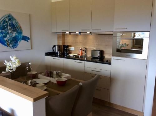 - une cuisine avec des placards blancs et une table à manger dans l'établissement Studio Hanna, à Kaprun