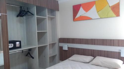 a bedroom with a bed and a book shelf at Lacqua diRoma 1 - Apartamentos JN in Caldas Novas