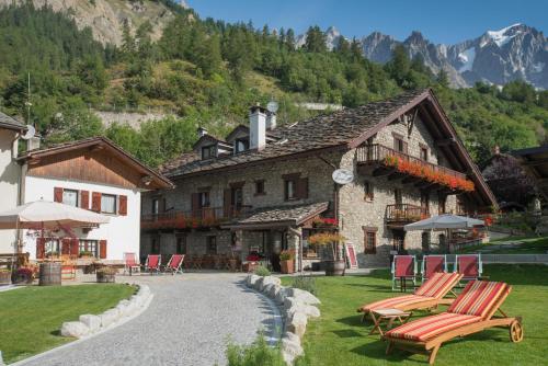 a building with chairs and tables in front of it at Hotel La Grange - Animal Chic Hotel in Courmayeur