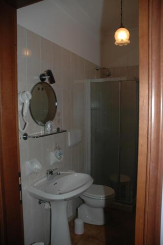 a bathroom with a sink and a toilet and a mirror at Hotel Valentino in Perosa Argentina