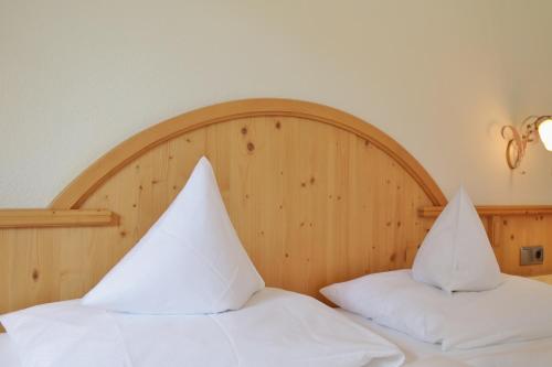 two white pillows on a bed with a wooden headboard at Haus Waldheim in Tux