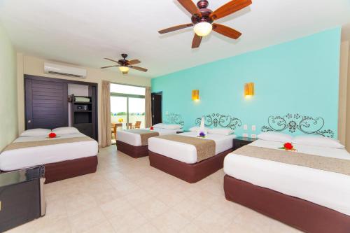 a bedroom with three beds and a ceiling fan at Angelo's Hotel in Playa del Carmen