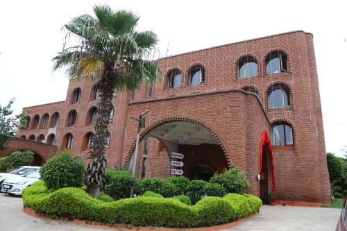 a red brick building with a palm tree in front of it at Magsons Resorts in Vrindāvan