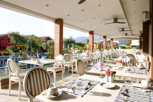a restaurant with white tables and chairs on a patio at Alexandra Golden Boutique Hotel-Adults Only in Chrysi Ammoudia
