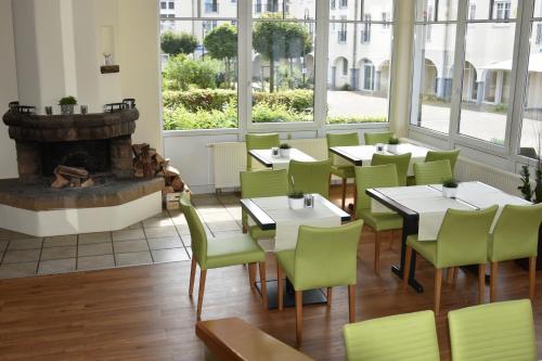 Landhotel Gillenfelder Hof في Gillenfeld: مطعم بطاولات وكراسي ومدفأة