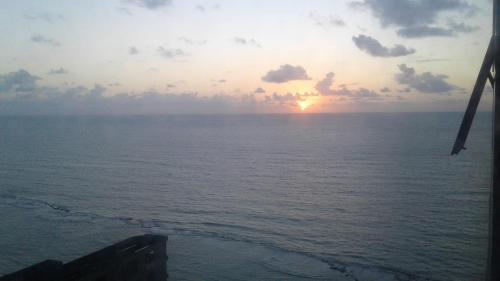 una puesta de sol sobre el océano desde un barco en Aconchegante Flat na Orla, en Recife