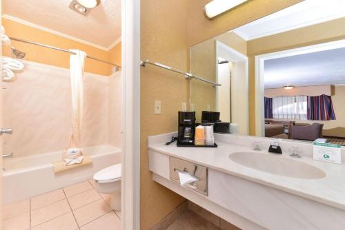 a bathroom with a sink and a toilet and a mirror at Executive Plus Inn and Suites in Elk City