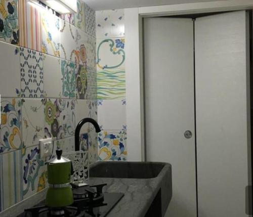サン・ヴィート・ロ・カーポにあるFresco Mare Bluのカラフルなタイルの壁、洗面台付きのバスルーム