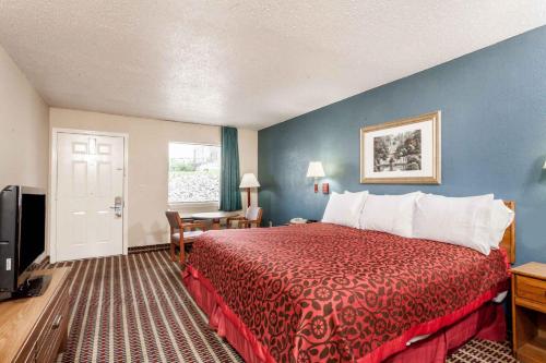 a hotel room with a bed with a red bedspread at Days Inn by Wyndham Nashville N Opryland/Grand Ole Opry in Nashville