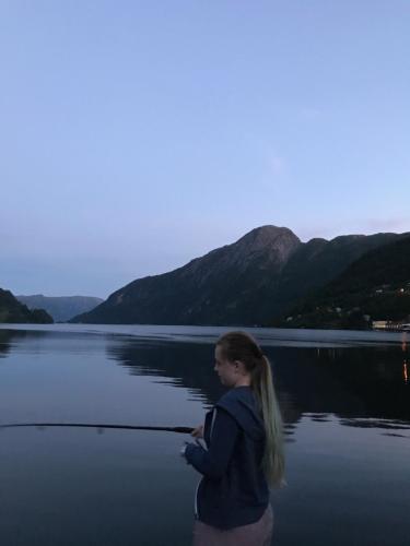 a girl fishing in a lake with mountains in the background at Sogn Hotel in Vadheim