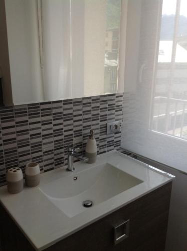 a white sink in a bathroom with a window at Appartamento Elisa 50m Trenino Rosso in Tirano