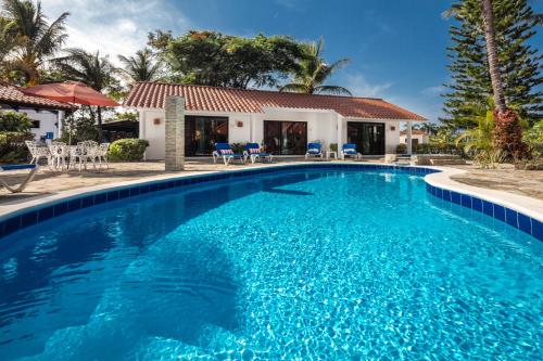 a swimming pool with blue water in front of a house at Garden By The Sea in Sosúa