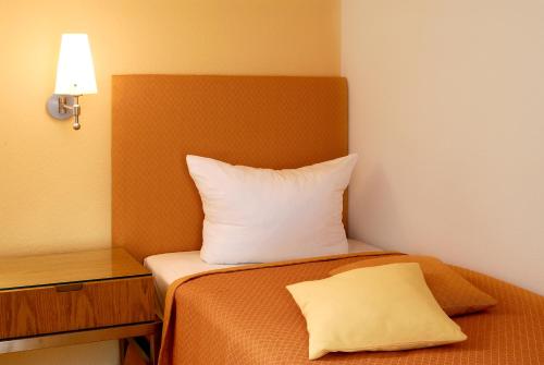 a bed with a white pillow on top of it at Restaurant-Hotel Maien in Lörrach