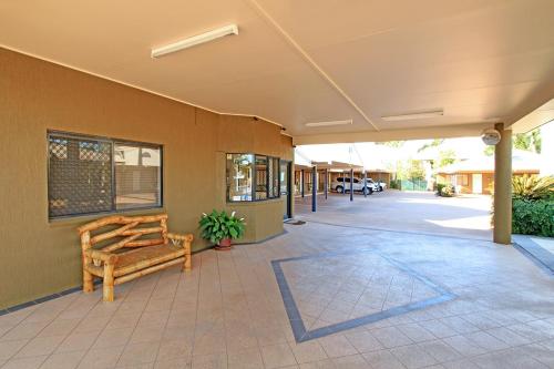 
a wooden bench sitting in front of a building at Rockhampton Palms Motor Inn in Rockhampton
