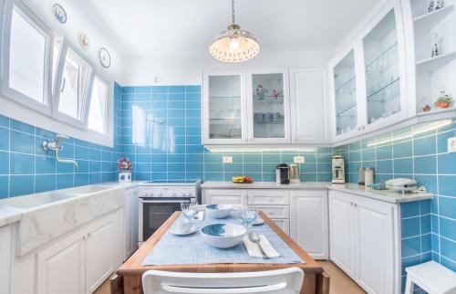 a kitchen with white cabinets and blue tiles at New Mykonos town house in Mýkonos City