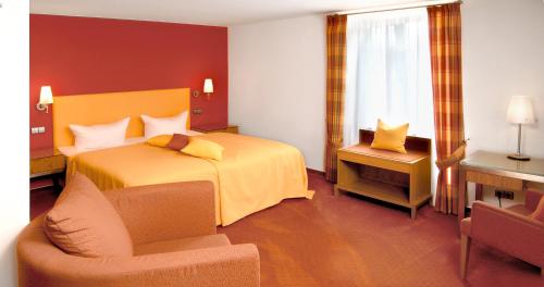 a hotel room with a bed and a chair at Restaurant-Hotel Maien in Lörrach