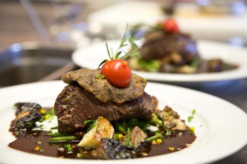 a plate of food with meat and a tomato on top at Restaurant-Hotel Maien in Lörrach