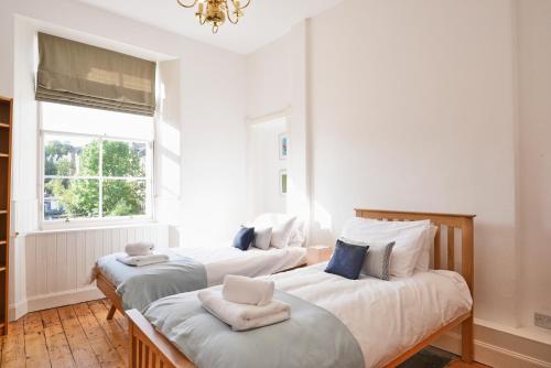 Duas camas num quarto branco com uma janela em Comely Bank Apartment em Edinburgo