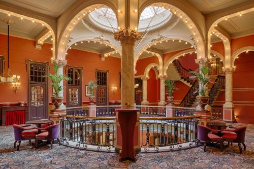 ein großes Gebäude mit einer Lobby mit einer Treppe in der Unterkunft Hotel Des Indes The Hague in Den Haag