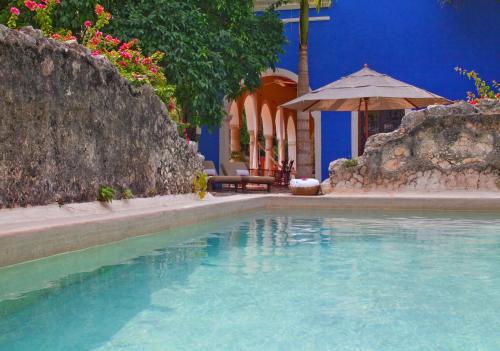 a swimming pool with an umbrella and a table and chairs at Hacienda San Jose Cholul in Tixkokob