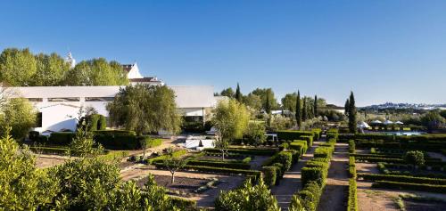 a garden in front of a white building at Convento do Espinheiro, Historic Hotel & Spa in Évora