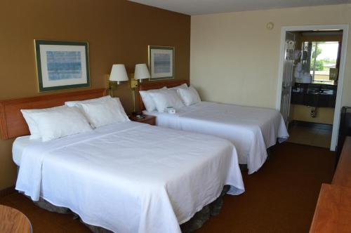two beds in a hotel room with white sheets at Ontario Airport Inn in Ontario