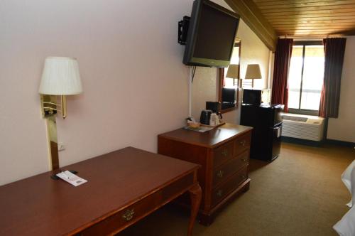 a hotel room with a desk and a tv on the wall at Ontario Airport Inn in Ontario