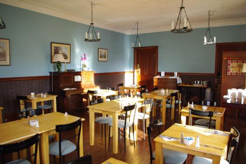 een restaurant met houten tafels en stoelen en een piano bij The Cuilfail Hotel in Kilmelfort
