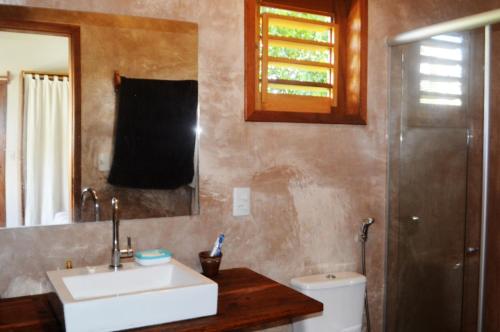 a bathroom with a sink and a mirror and a toilet at Residence Bons Ventos Jeri in Jericoacoara