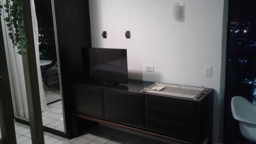 ein Badezimmer mit einem TV auf einer Kommode mit einem Spiegel in der Unterkunft Aconchegante Flat na Orla in Recife