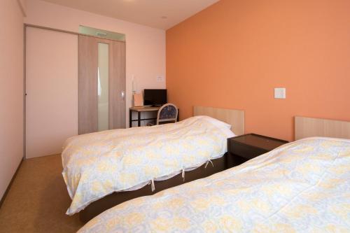 a bedroom with two beds and a desk with a computer at Hotel Asahi Grandeur Fuchu in Fuchu