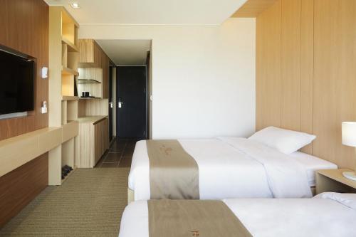 a hotel room with two beds and a flat screen tv at Royal Emporium Incheon Airport in Incheon